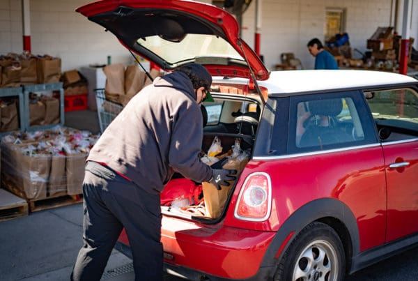 Volunteer loading groceries into a car at the ROC weekly distribution.